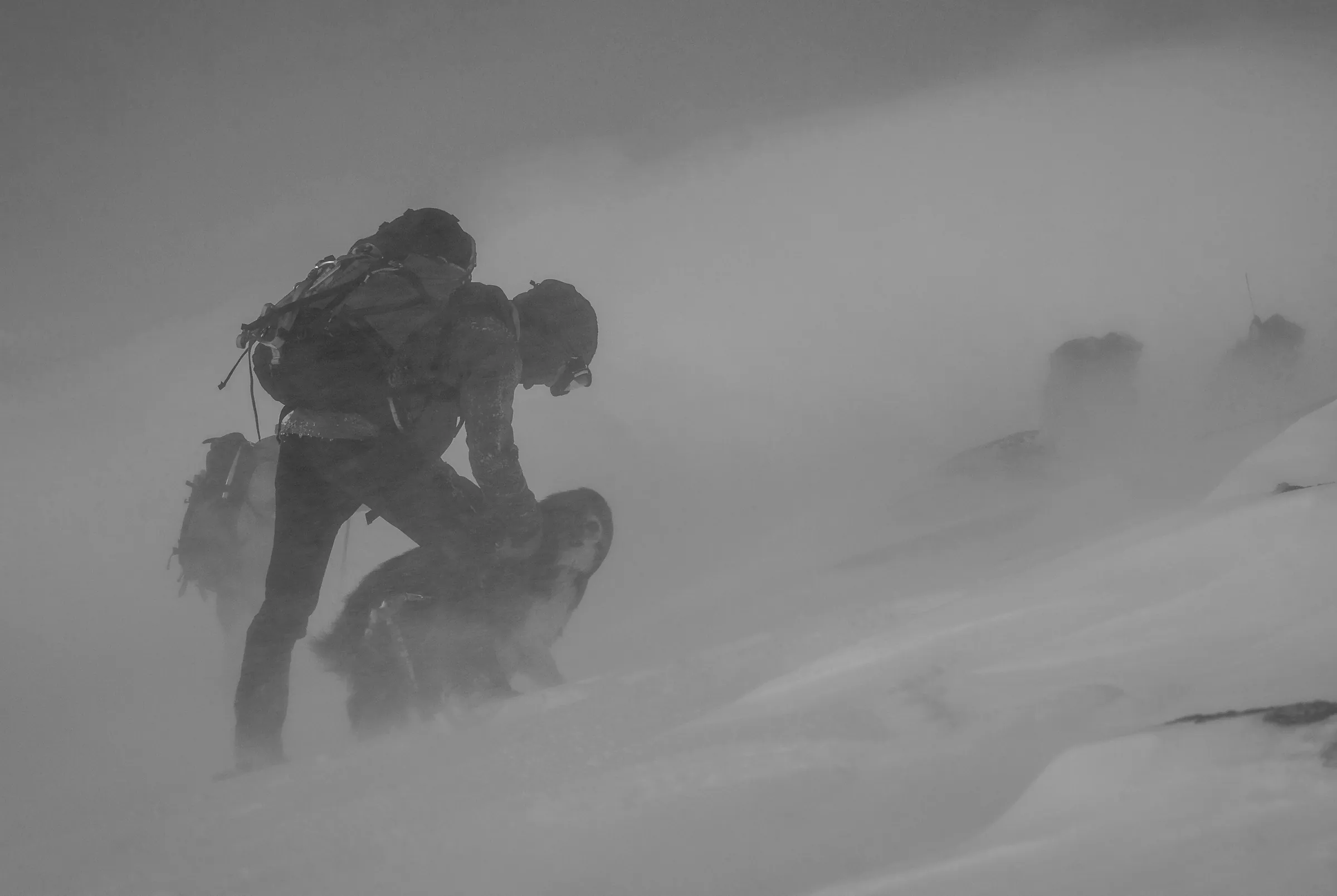 A rescuer working on an exposed mountainside in a blizzard